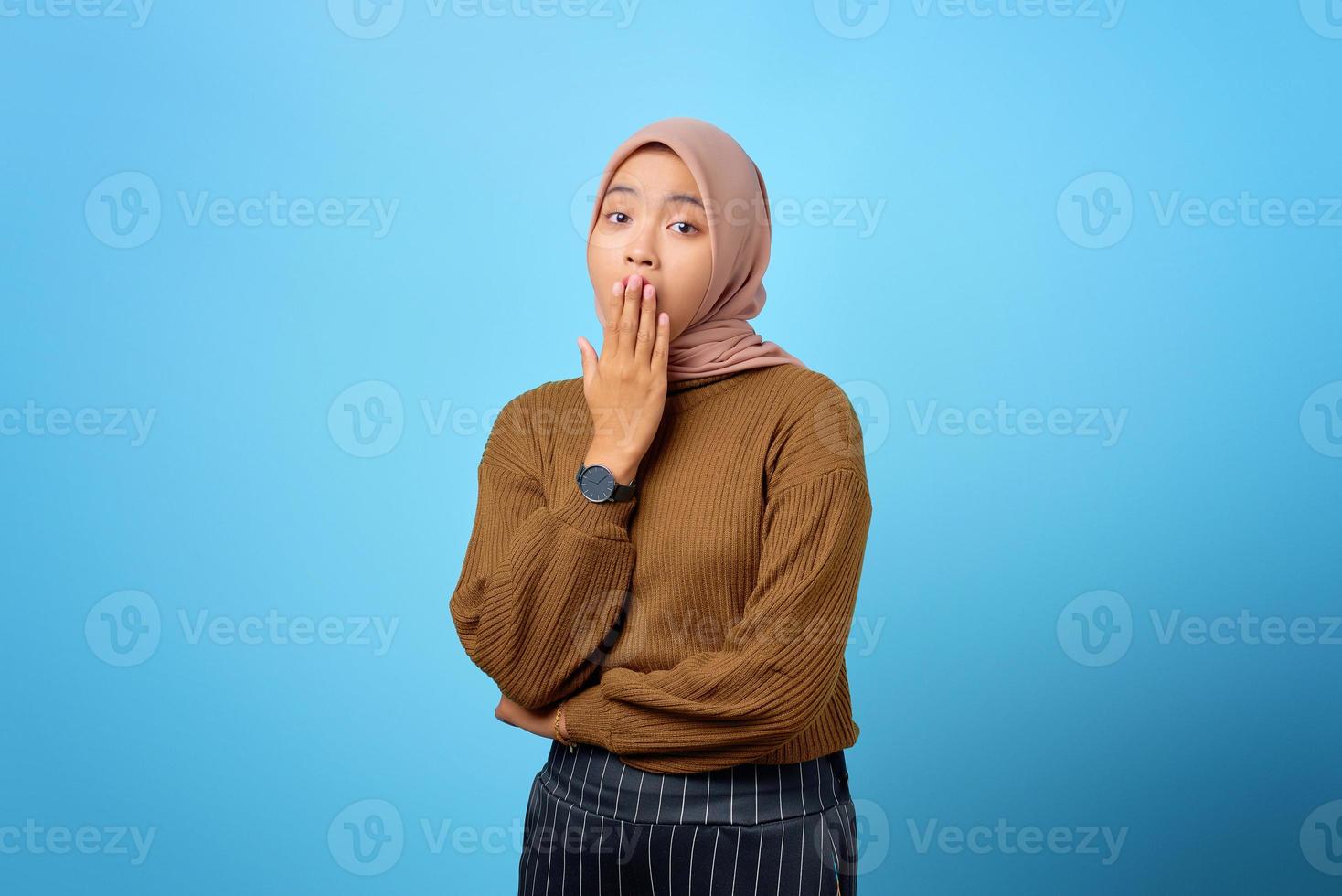 jonge aziatische vrouw geeuwen moe die mond bedekt met hand op blauwe achtergrond foto