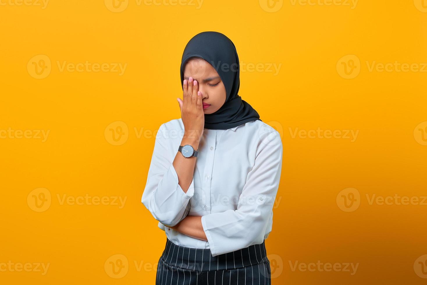 portret van uitgeputte jonge aziatische vrouw wrijft in de ogen en voelt zich moe op gele achtergrond foto