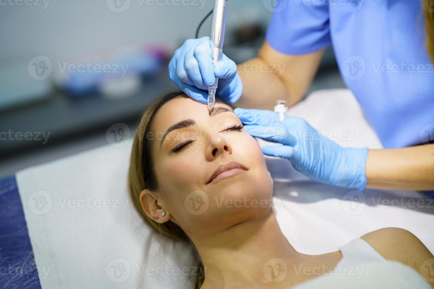 permanente make-up voor wenkbrauwen van mooie vrouw in een schoonheidssalon. micropigmentatie behandeling. foto