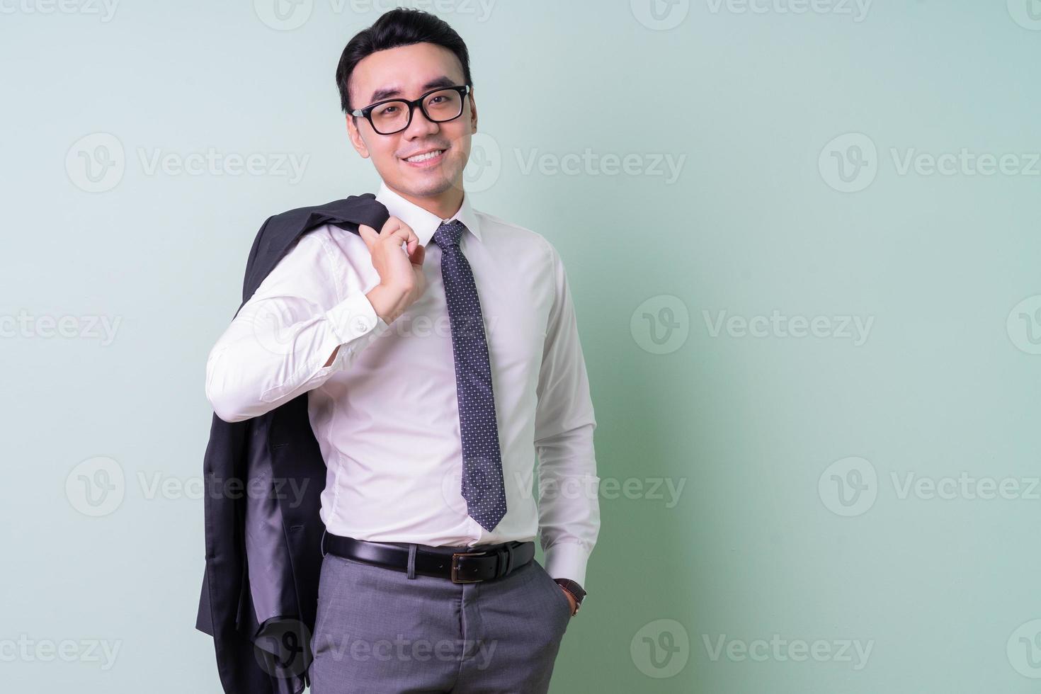 jonge Aziatische zakenman die zich voordeed op groene achtergrond foto