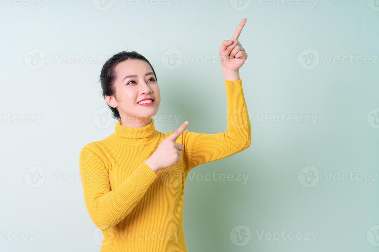 mooie jonge aziatische vrouw die sweater op groene achtergrond draagt foto