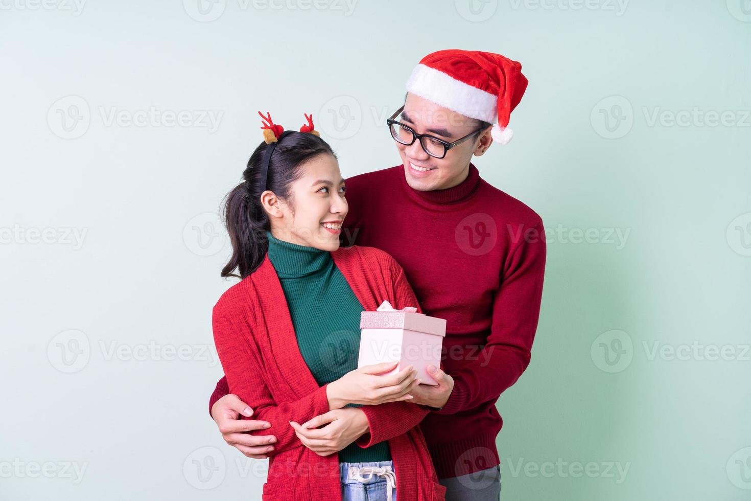 jonge Aziatische paar poseren op groene achtergrond met kerst concept foto