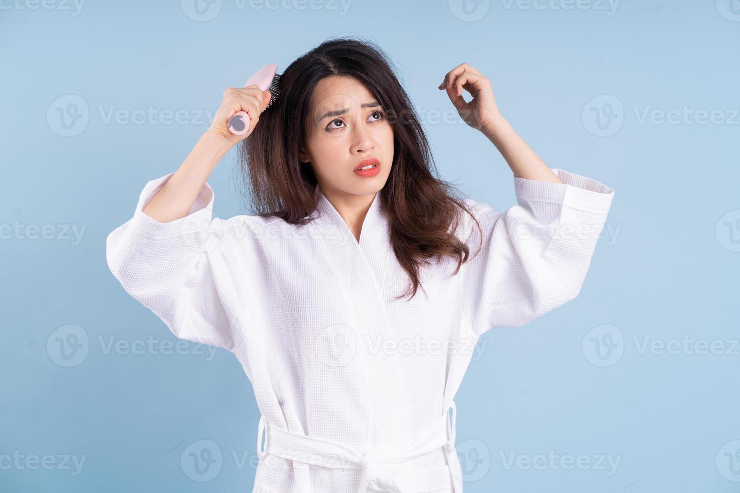 jonge aziatische vrouw die badjas op blauwe achtergrond draagt foto