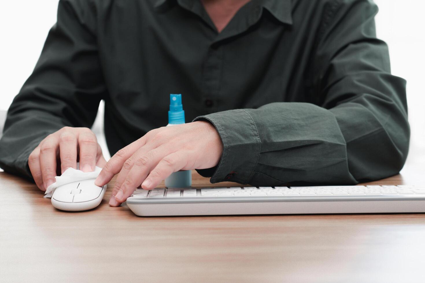 dichtbij omhoog hand- een Mens schoonmaak muis van computer en ontsmetting van werkruimte. desinfecteren doekjes naar veeg oppervlakte van bureau Bij kantoor. hou op de verspreiding foto