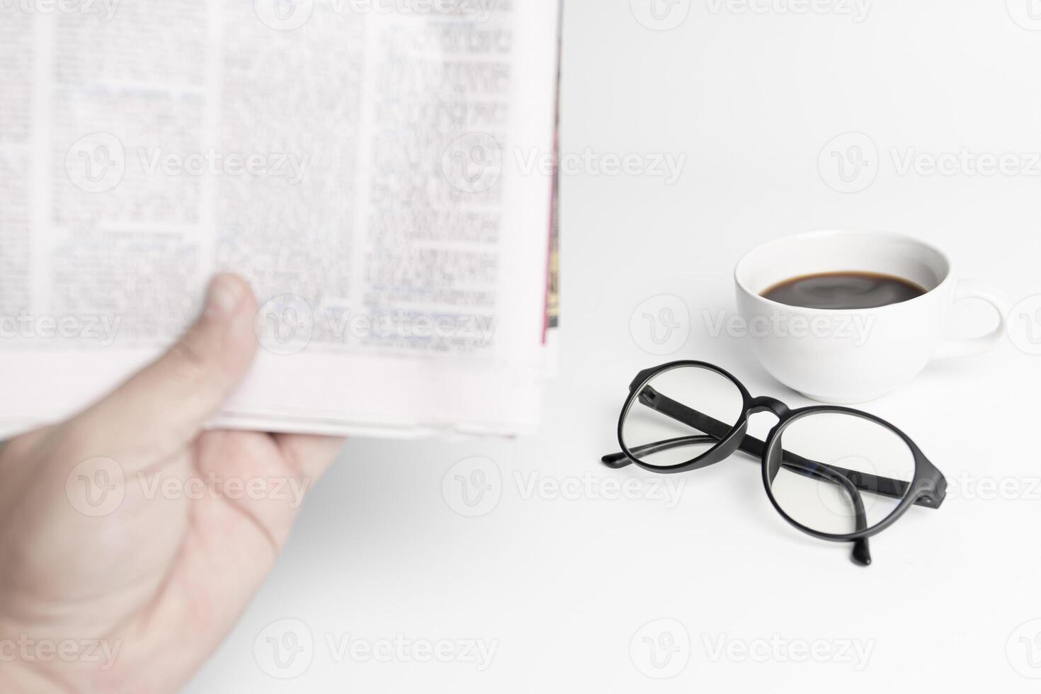 koffie kopje, glazen, en een Mens lezen nieuws papier Aan de wit tafel foto