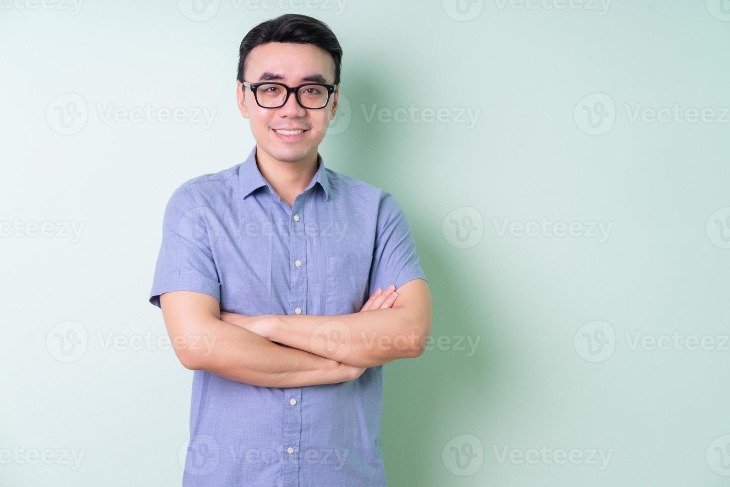 jonge Aziatische zakenman die zich voordeed op groene achtergrond foto