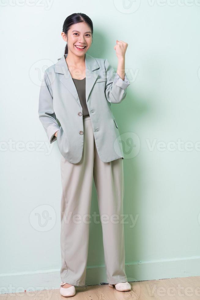 jonge Aziatische zakenvrouw die een groen pak draagt op een groene achtergrond foto