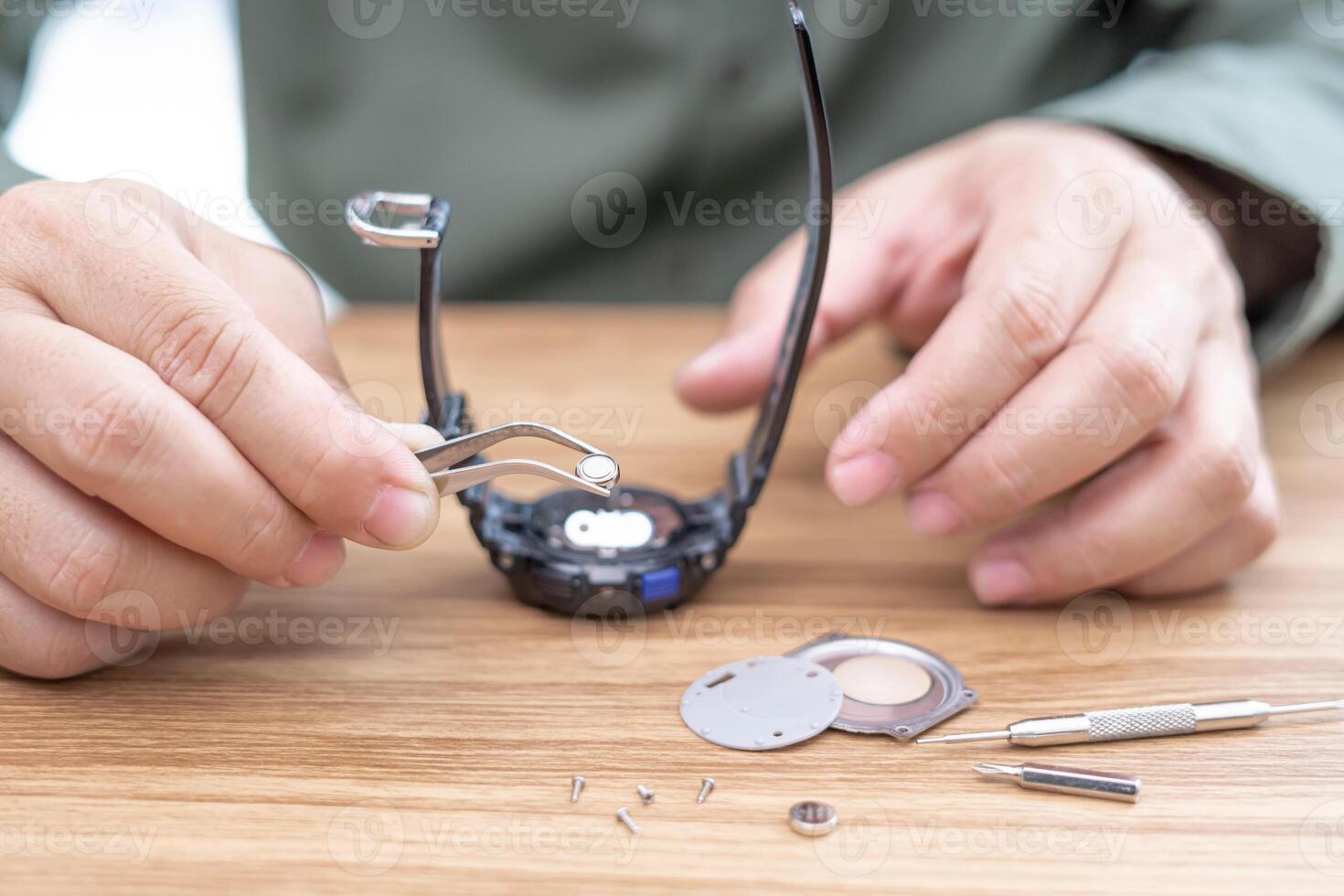 een Mens gebruik tang naar klem de digitaal kijk maar accu verwijderen en verandering in repareren gebroken polshorloges Aan wit tafel foto