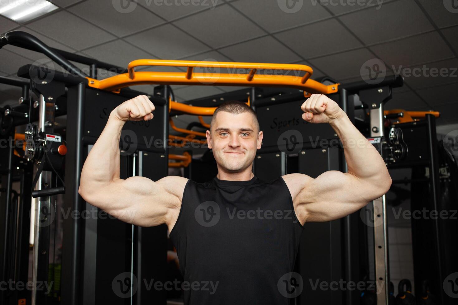 jong knap trainer in een zwart uniform tegen achtergrond van een simulator in Sportschool. gespierd atletisch lichaam van een bodybuilder, coachen, individu sport- en gewicht verlies cursussen. portret. sterk foto