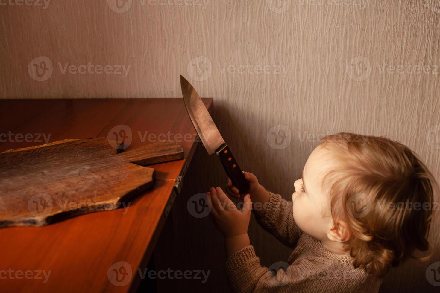 de kind trekt een mes van de tafel. de kind kan snee, kinderen huis gevaren. een weinig een jaar oud meisje met een mes. foto