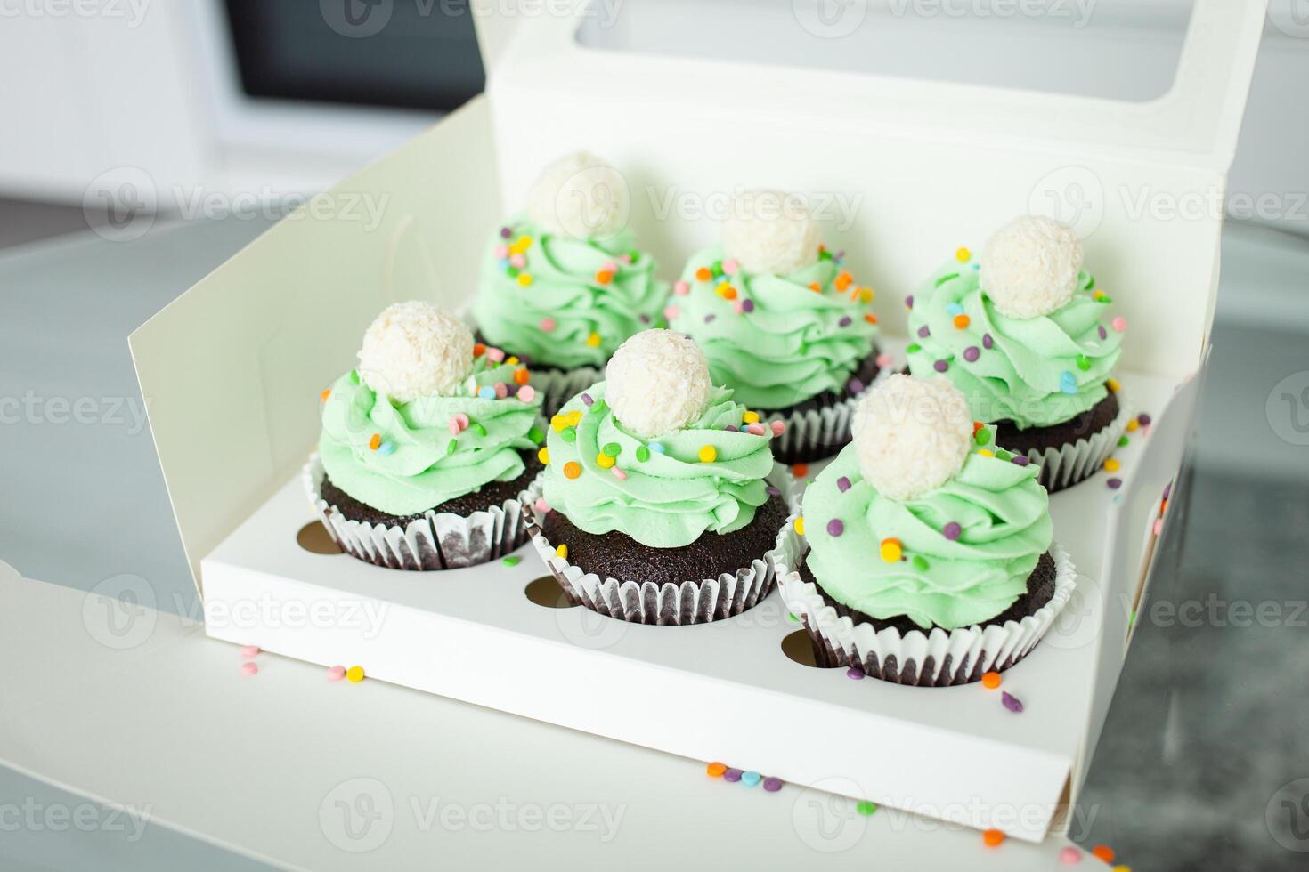 wit doos. gebakje chef professioneel bereid cupcakes in het formulier van Kerstmis bomen. heerlijk snoepgoed voor ieder vakantie, geschenk. groen geslagen room. foto