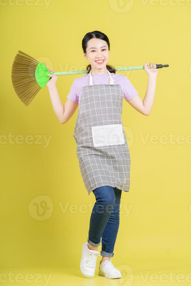 jonge Aziatische huisvrouw die zich voordeed op gele achtergrond foto