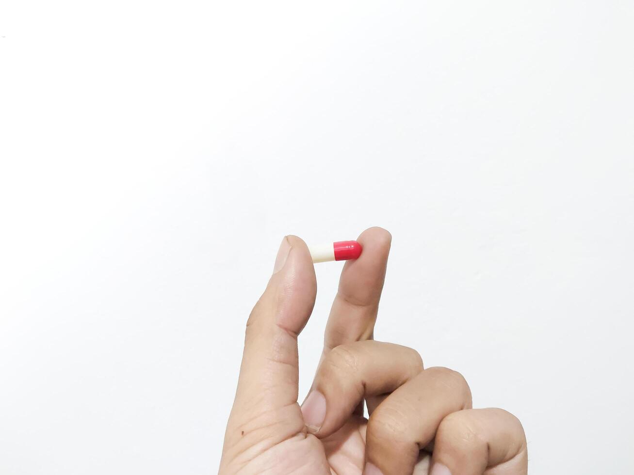 vingers van een hand- Holding een capsule pil geïsoleerd Aan een wit achtergrond foto