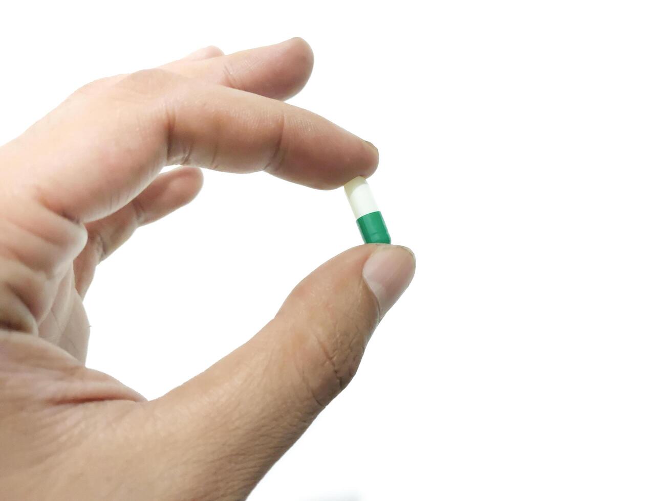 vingers van een hand- Holding een capsule pil geïsoleerd Aan een wit achtergrond foto