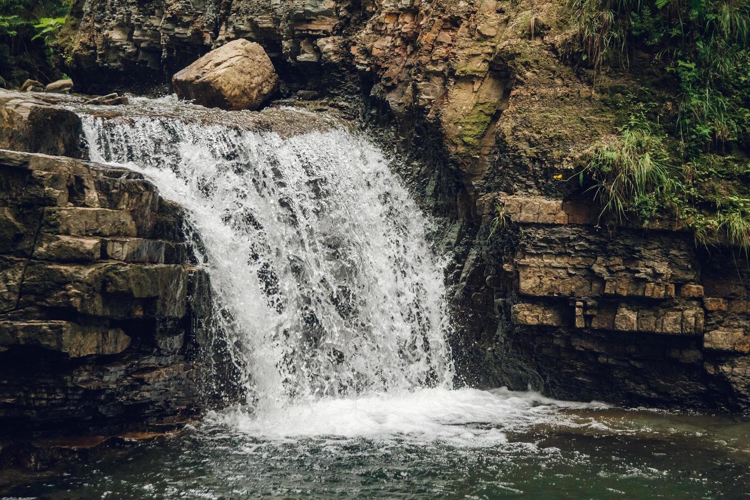 kleine waterval met een meer tussen rotsen en bos foto