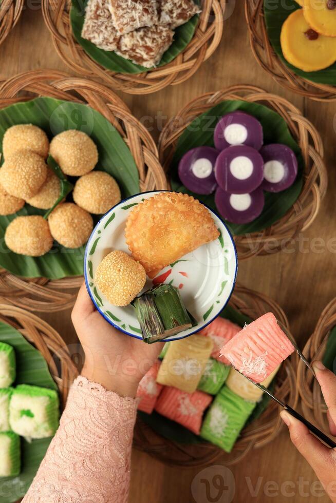 vrouw hand- zetten kue basah traditioneel Indonesisch voedsel jajanan pasar naar glazuur bord foto