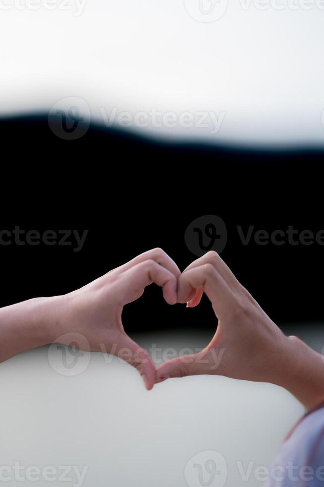 vrouw verheven haar handen en gemaakt hart symbool naar uitdrukken betekenis van liefde vriendschap en vriendelijkheid naar haar vrienden en liefhebbers. vrouw toepassingen haar handen naar maken een hart symbool dat middelen liefde en vriendschap. foto