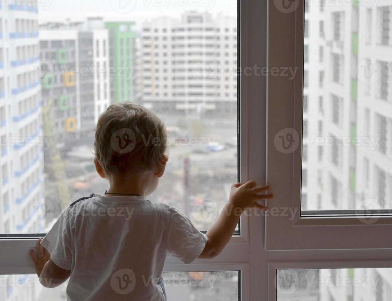 mooie babyjongen met kind gezicht poseren fotograaf in de buurt van raam foto