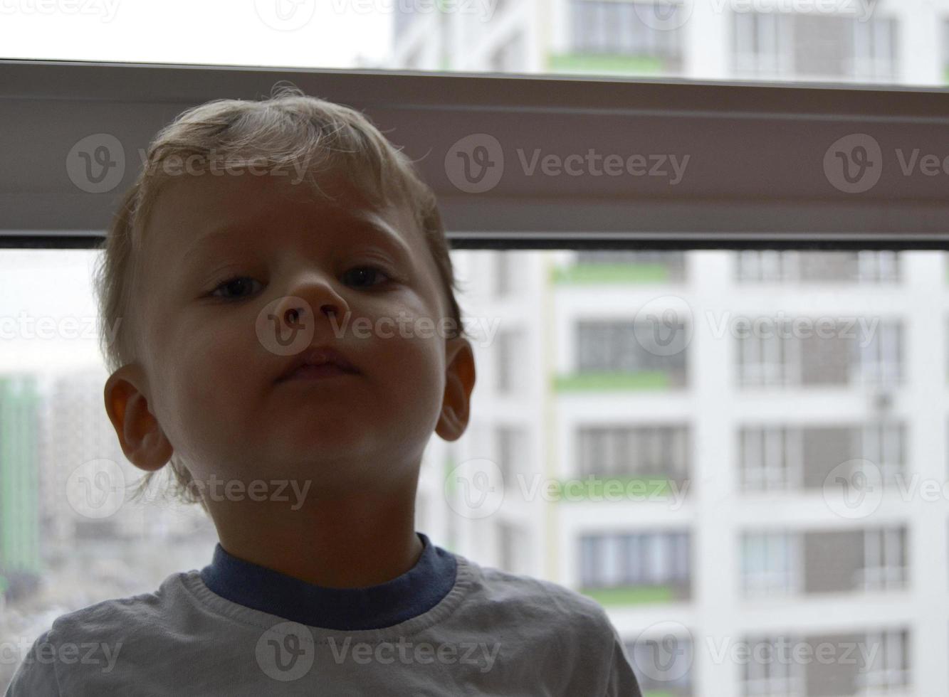 mooie babyjongen met kind gezicht poseren fotograaf in de buurt van raam foto