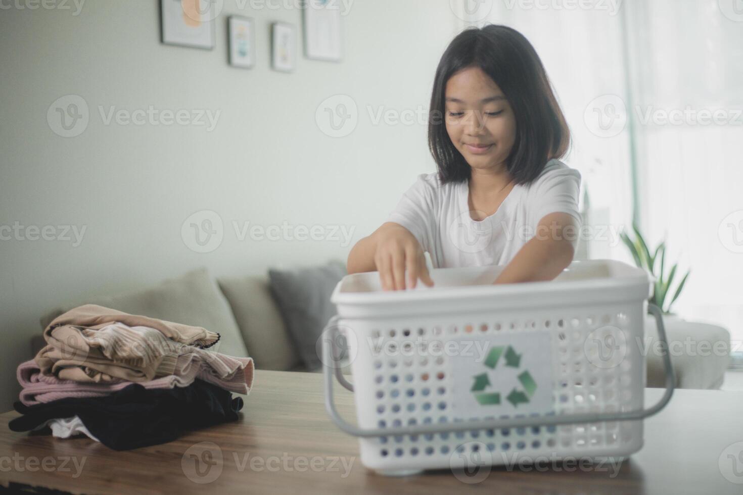 recycle kleren concept. Aziatisch weinig meisje met een recycling doos vol van kleren. foto