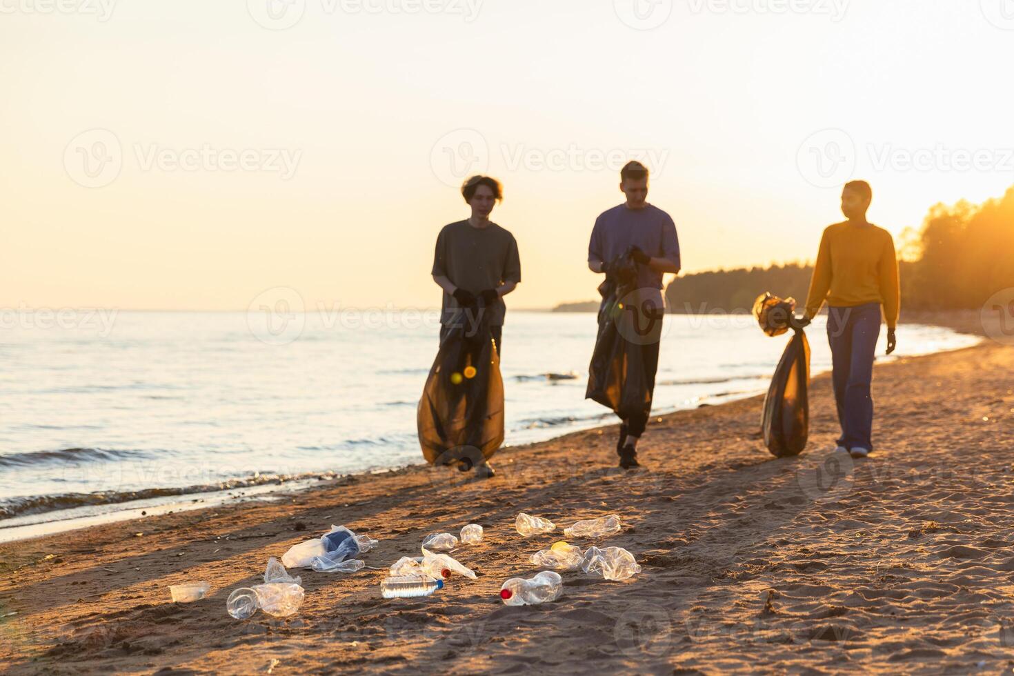 aarde dag. vrijwilligers activisten team verzamelt vuilnis schoonmaak van strand kust- zone. vrouw mans met uitschot in vuilnis zak Aan oceaan oever. milieu behoud kust- zone schoonmaak foto