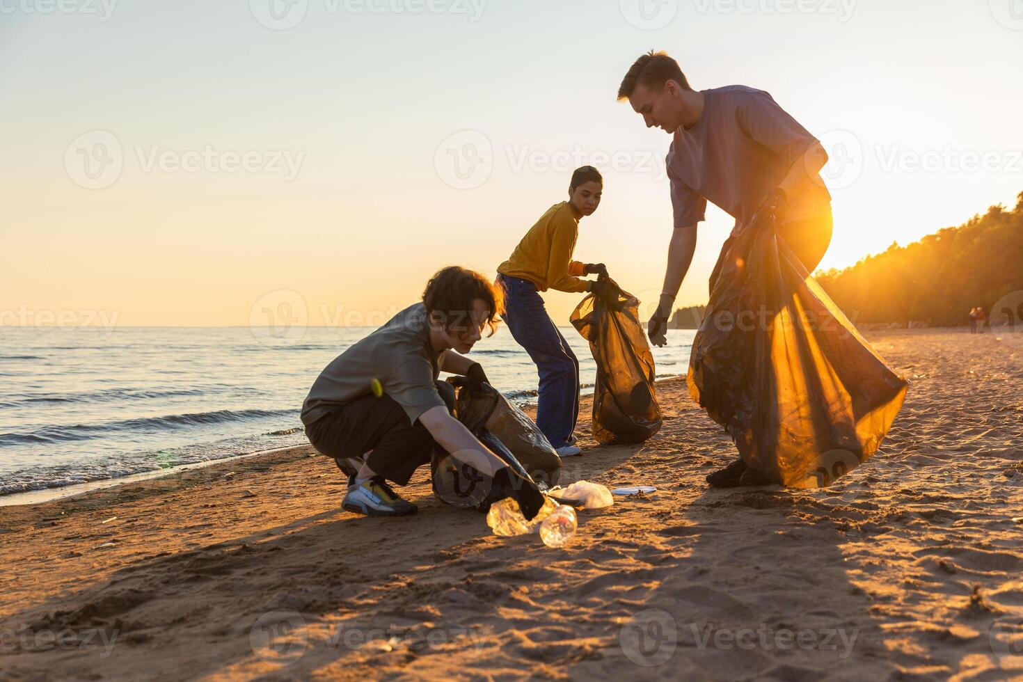 aarde dag. vrijwilligers activisten team verzamelt vuilnis schoonmaak van strand kust- zone. vrouw mans zet plastic uitschot in vuilnis zak Aan oceaan oever. milieu behoud kust- zone schoonmaak foto