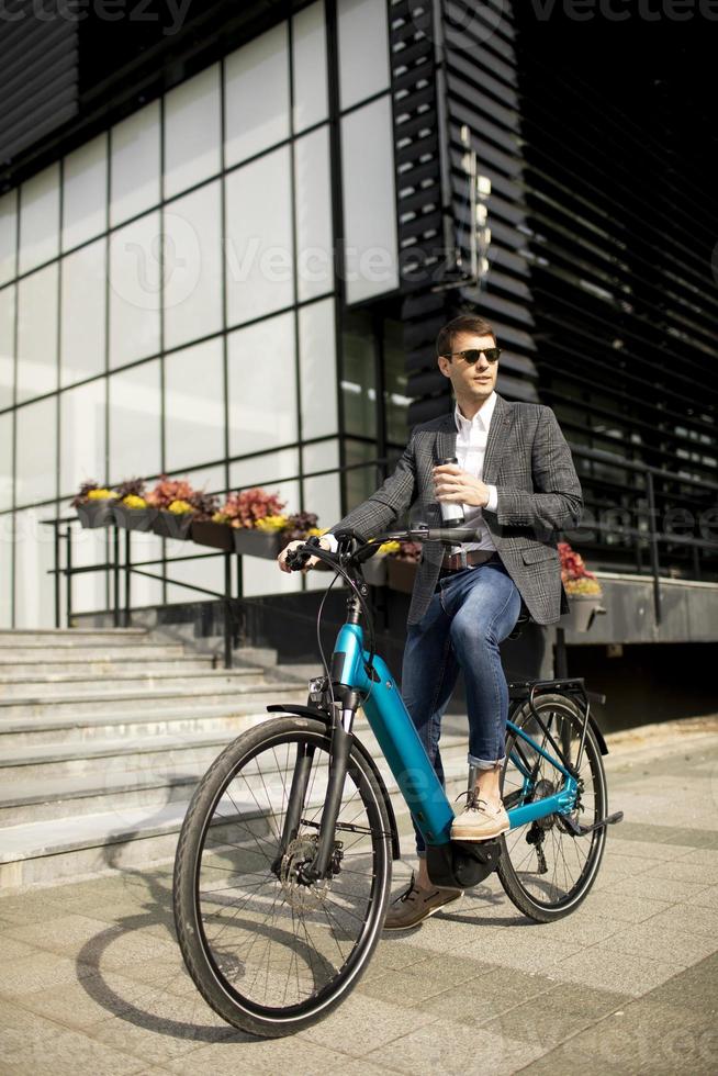 jonge zakenman op de ebike met afhaalkoffiekopje foto