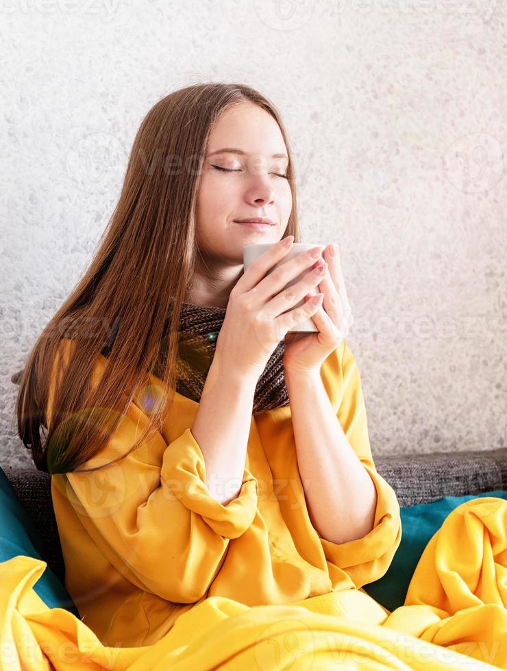 vrouw genietend van kopje koffie of thee zittend op een bank foto