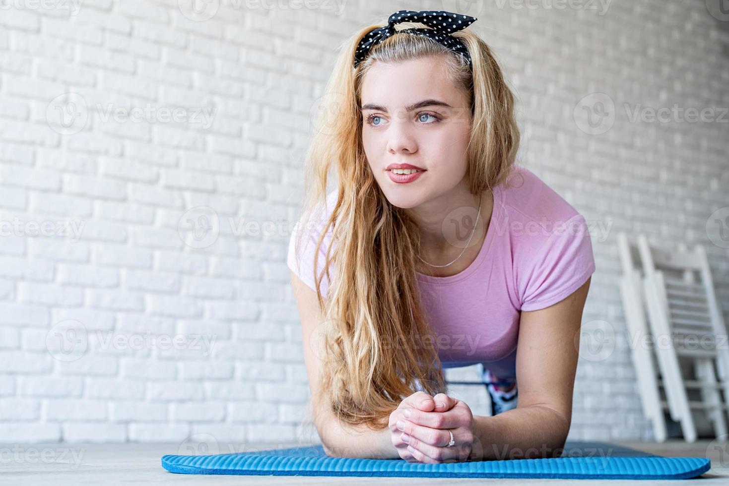 atletische vrouw die thuis op een fitnessmat traint op een witte bakstenen muurachtergrond foto