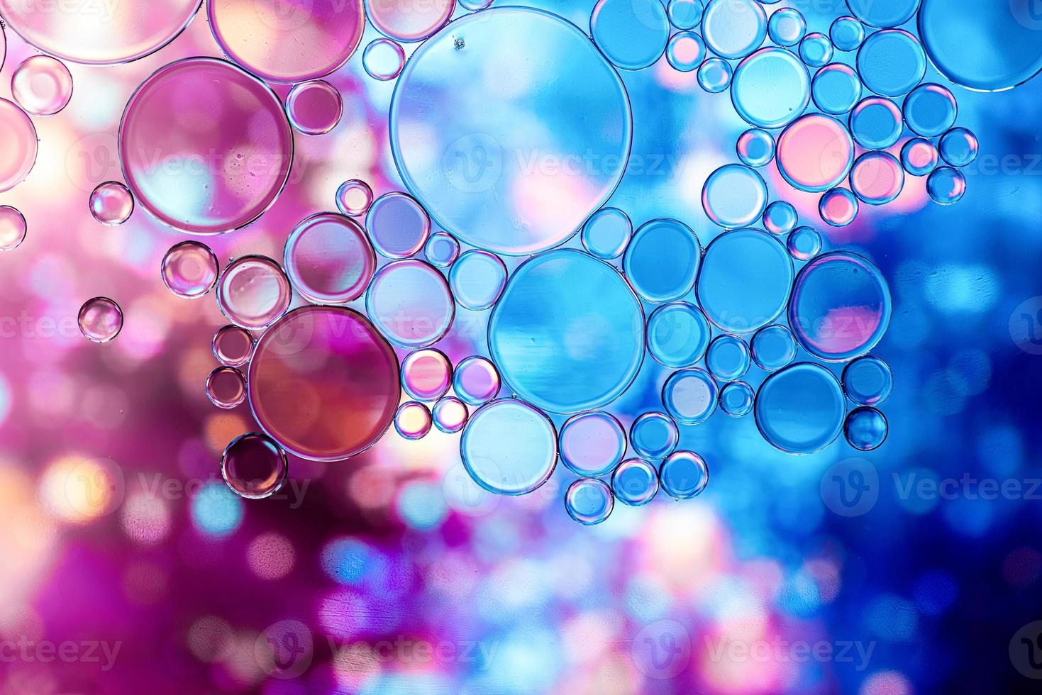 blauwe en paarse oliebellen in water met abstract patroon foto