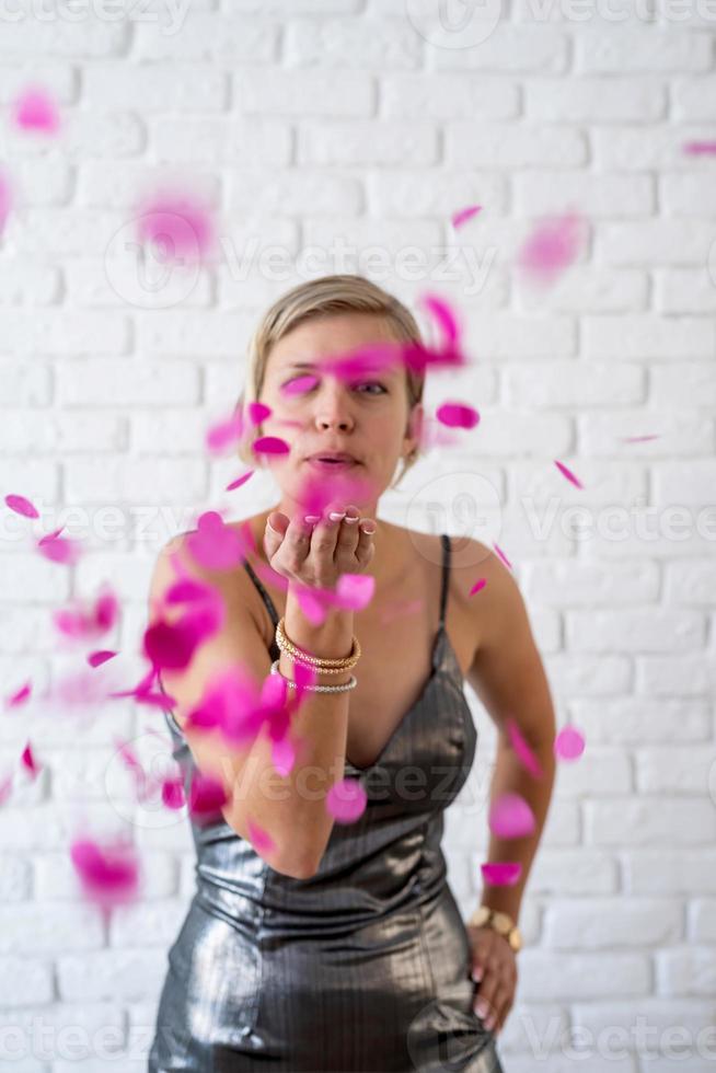 kaukasische vrouw die kleurrijke confetti de lucht in blaast foto