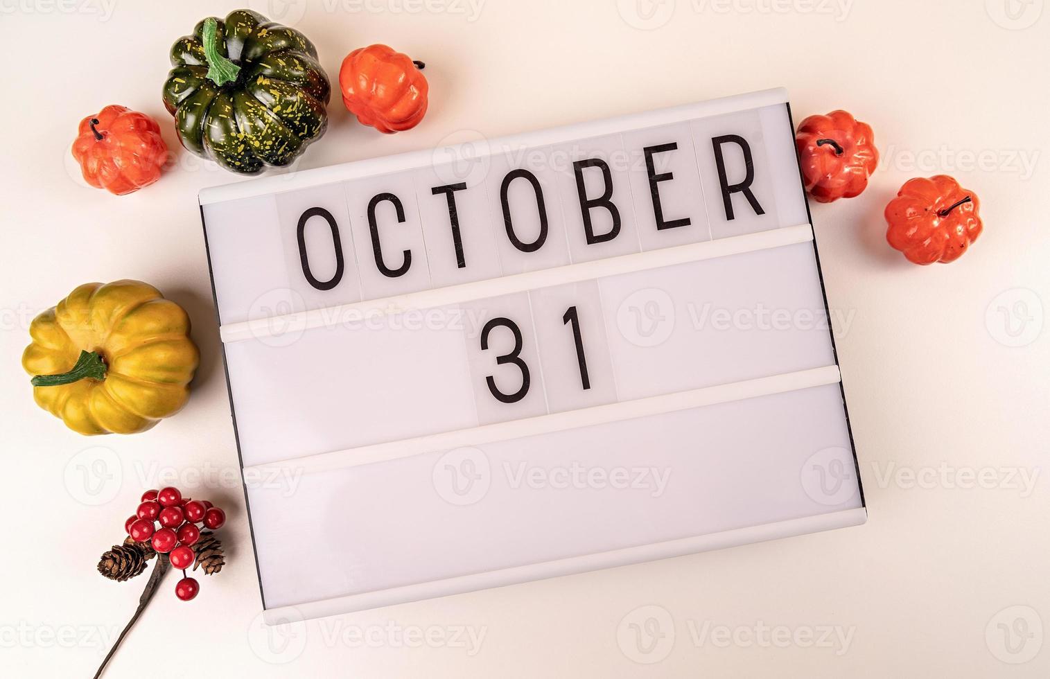 31 oktober lichtbak op witte tafel met pompoenen verspreid over foto