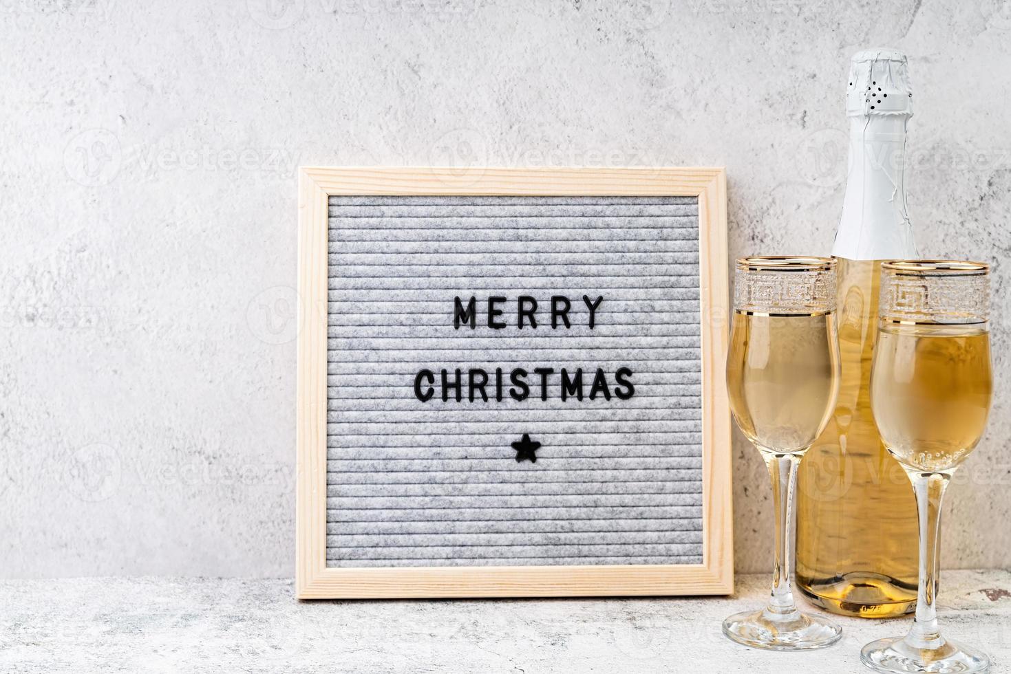 vilten letterbord vrolijk kerstfeest op tafel met champagneglazen en fles foto