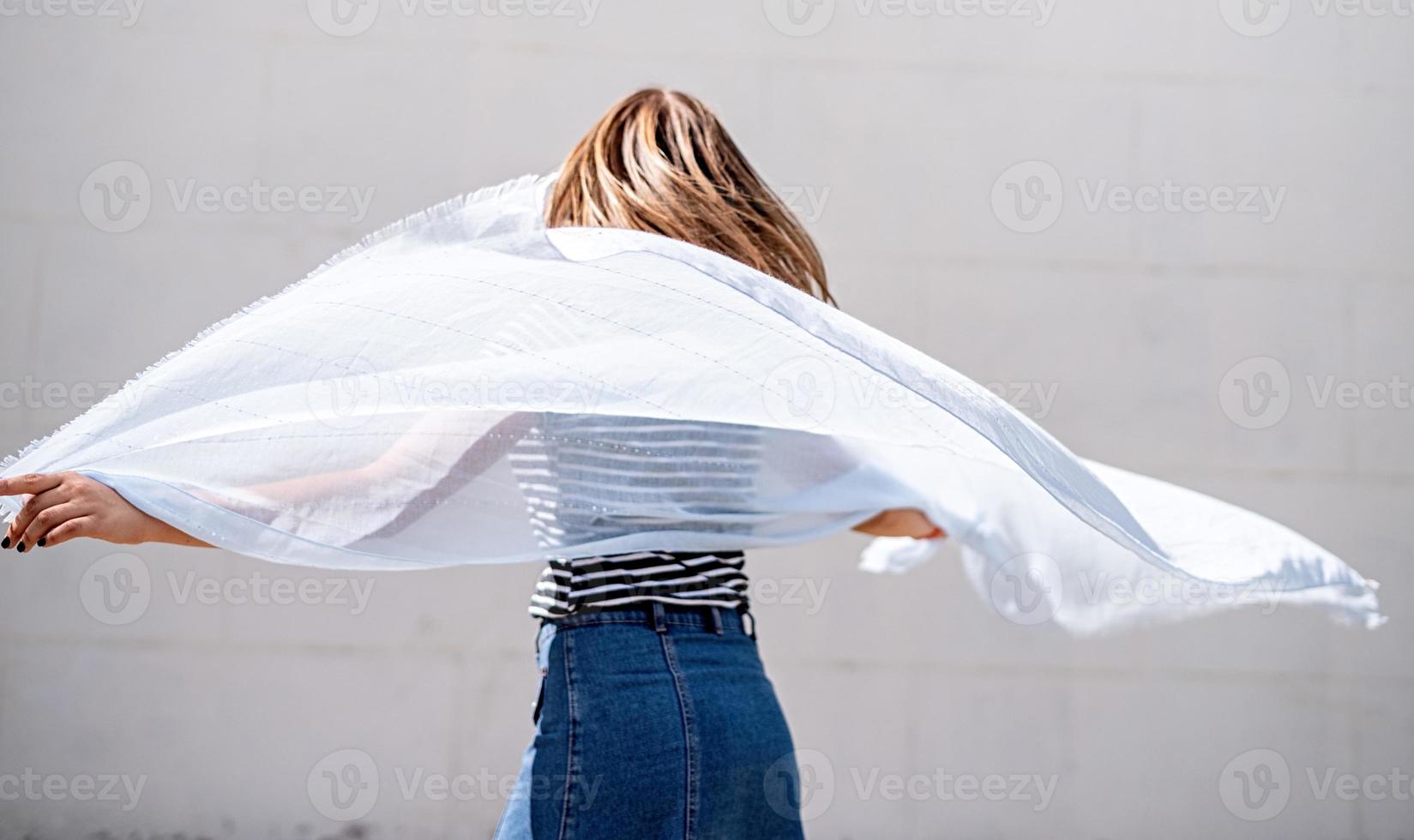 jonge vrouw met een blauwe stof die zich omdraait op een grijze achtergrond foto