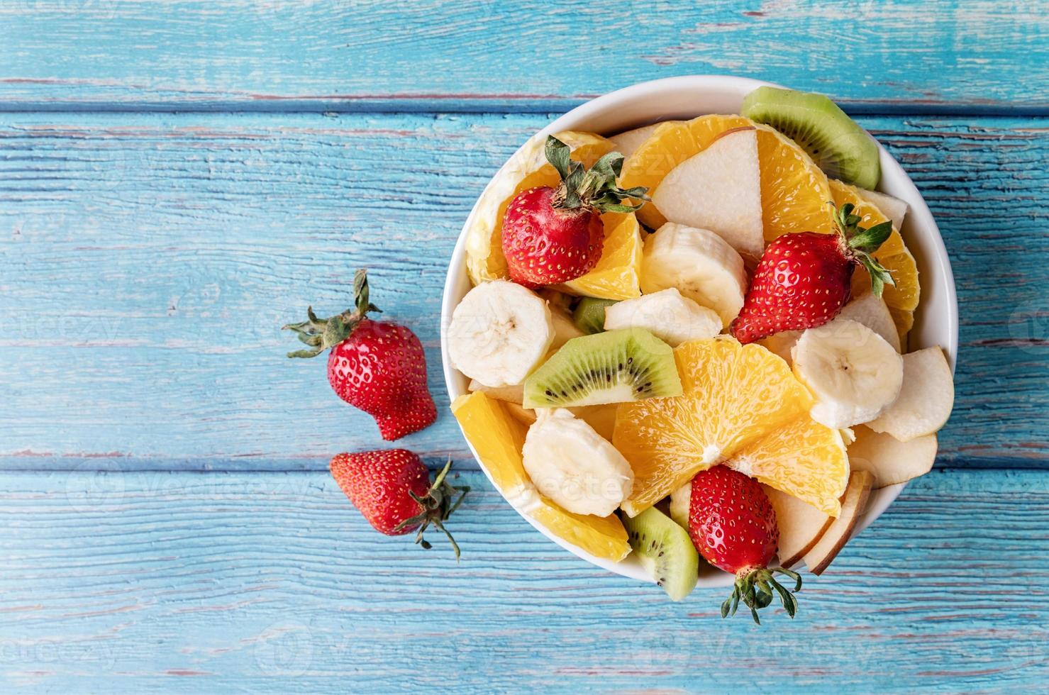 verse fruitsalade op blauwe houten achtergrond bovenaanzicht kopie ruimte foto