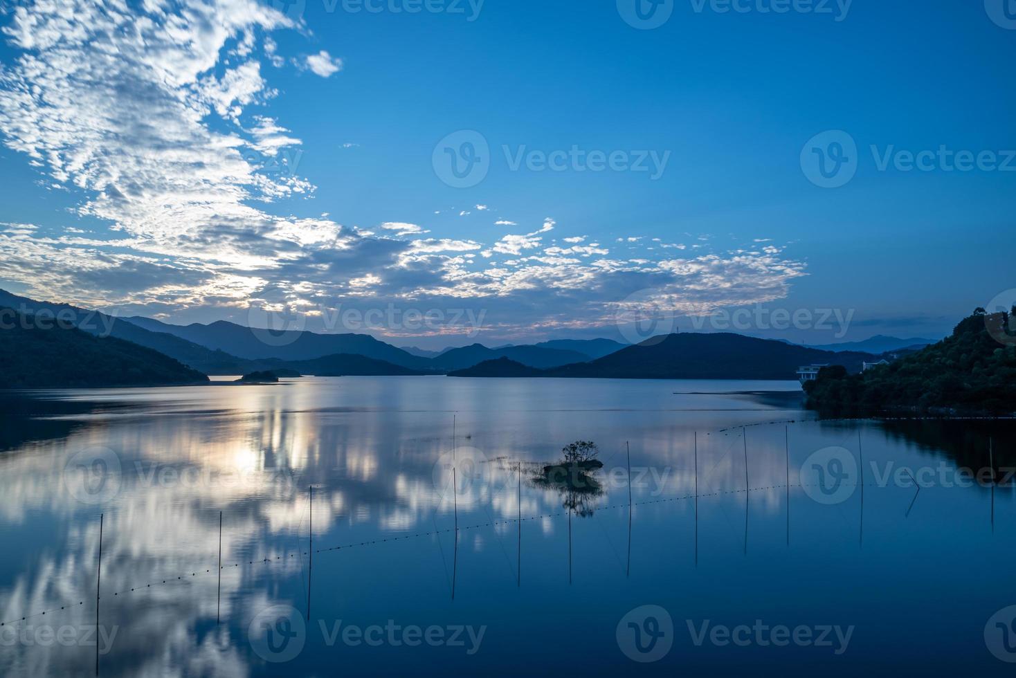 het avondmeer weerspiegelde de zonsonderganggloed en de bergen foto