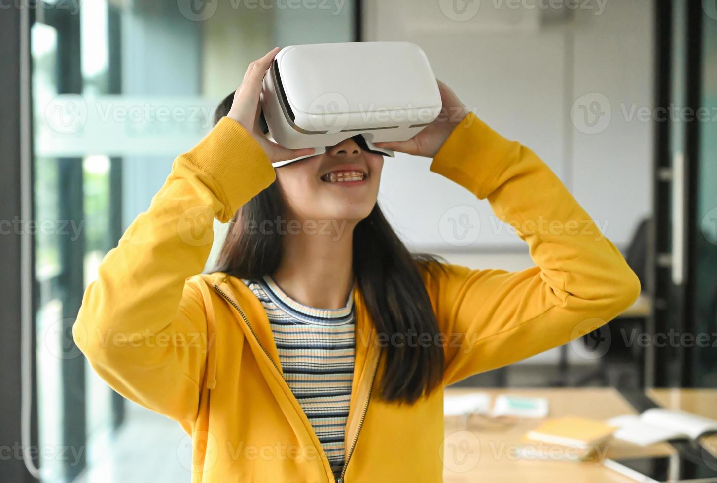 aziatisch meisje dat een geel shirt draagt, gebruikt de vr-headset. zij lacht. foto