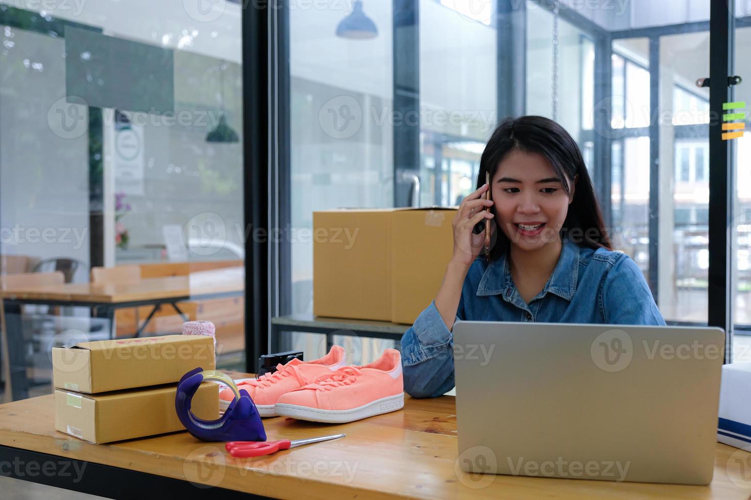 de pakketbezorger gebruikt een mobiele telefoon om met de klant te praten en de status te controleren met een laptop. foto