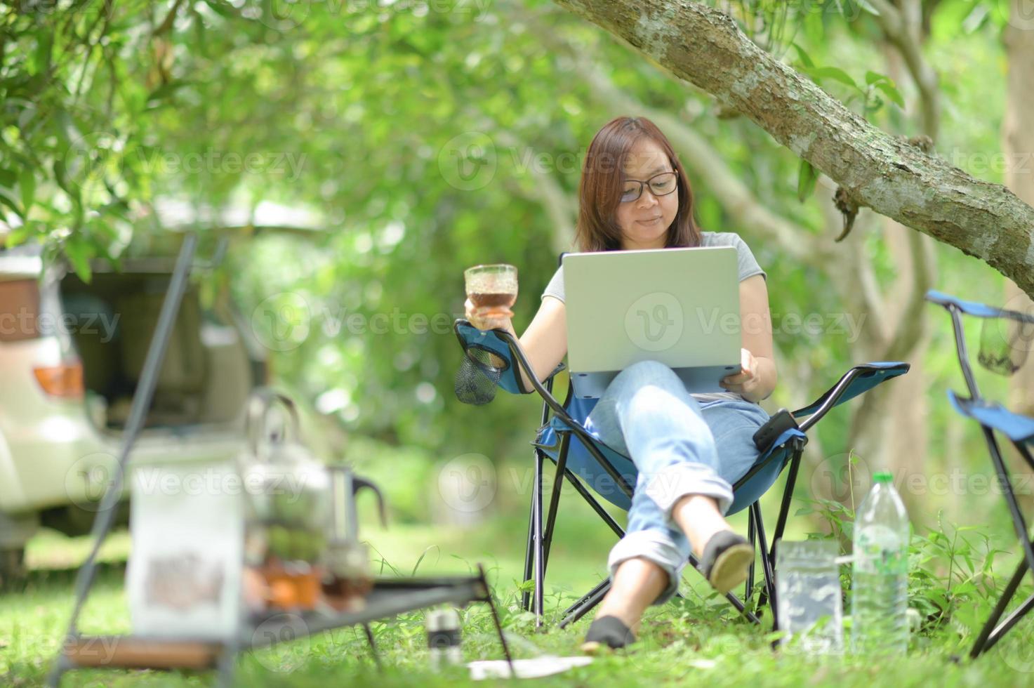 een vrouw die tijdens het kamperen met een laptop werkt. foto