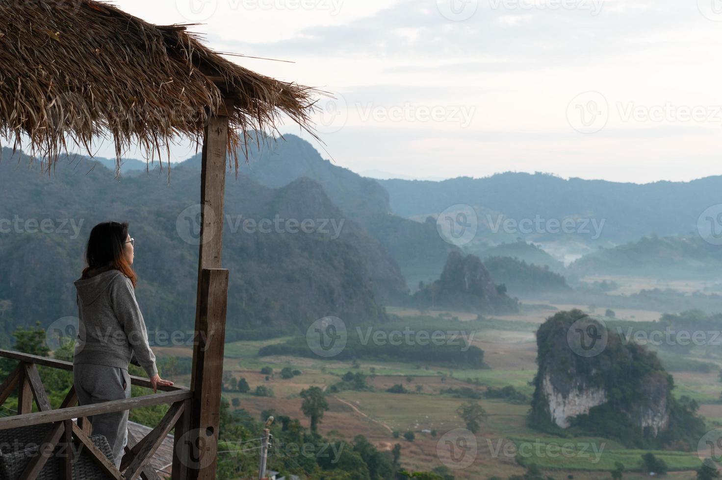 jonge aziatische vrouw voelt zich ontspannen en kijkt 's ochtends naar het landschapsbeeld van de vallei en de bergen. reis- en vakantieconcept foto