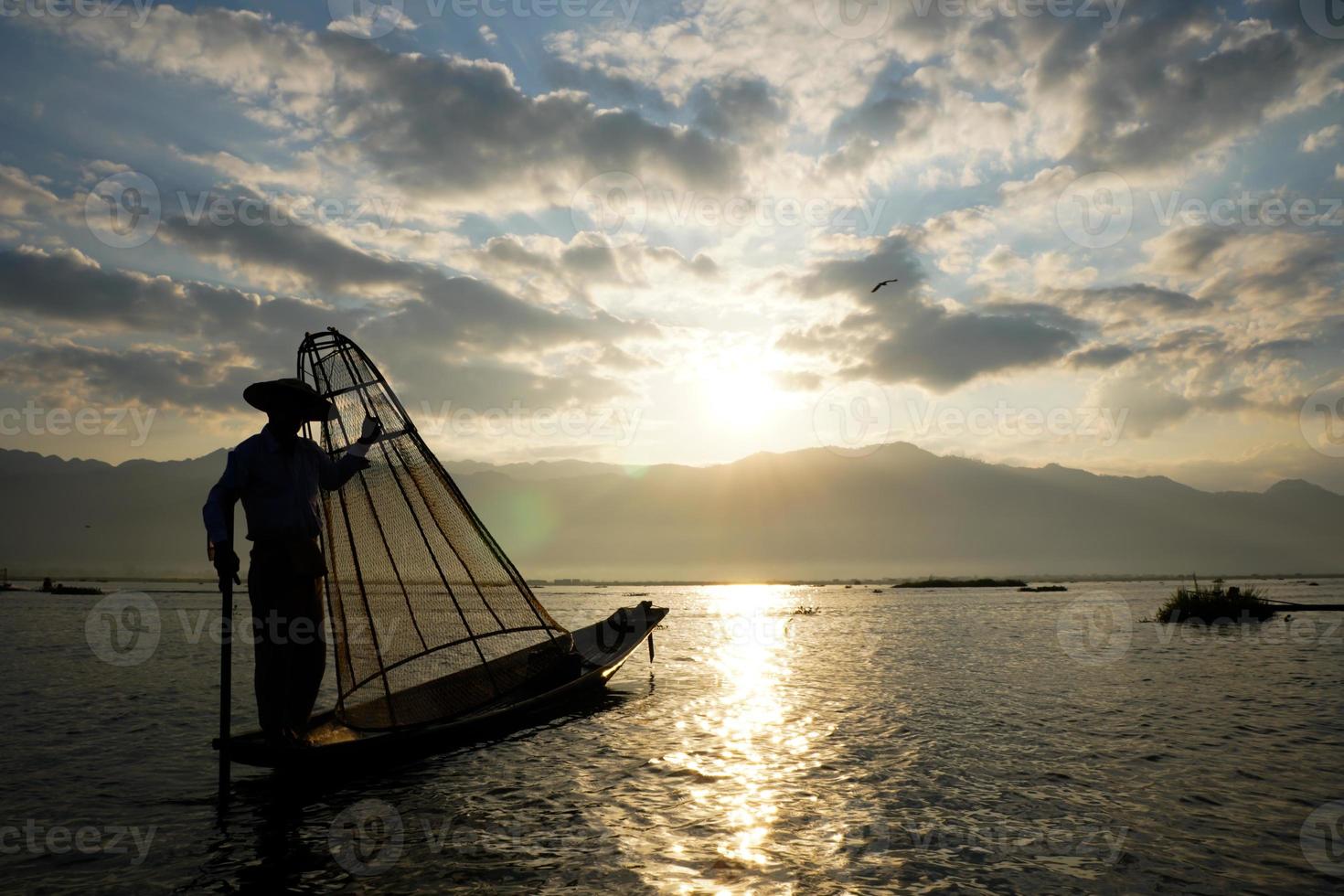 silhouet van lokale visser die kippenhok gebruikt om bij zonsopgang in het Inlemeer te vangen foto