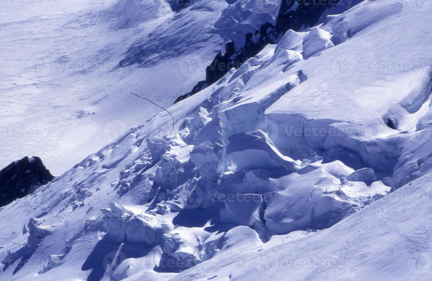 een Mens skiën naar beneden een besneeuwd berg kant foto