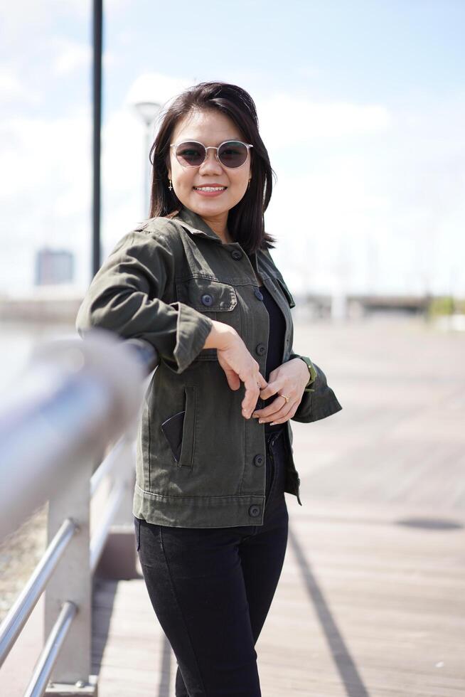 jong mooi Aziatisch vrouw vervelend jasje en zwart jeans poseren buitenshuis foto