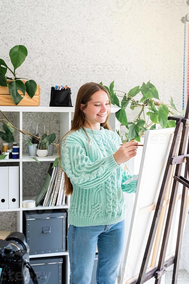 jonge tienervrouw die een kleurenpalet vasthoudt en in haar studio werkt foto