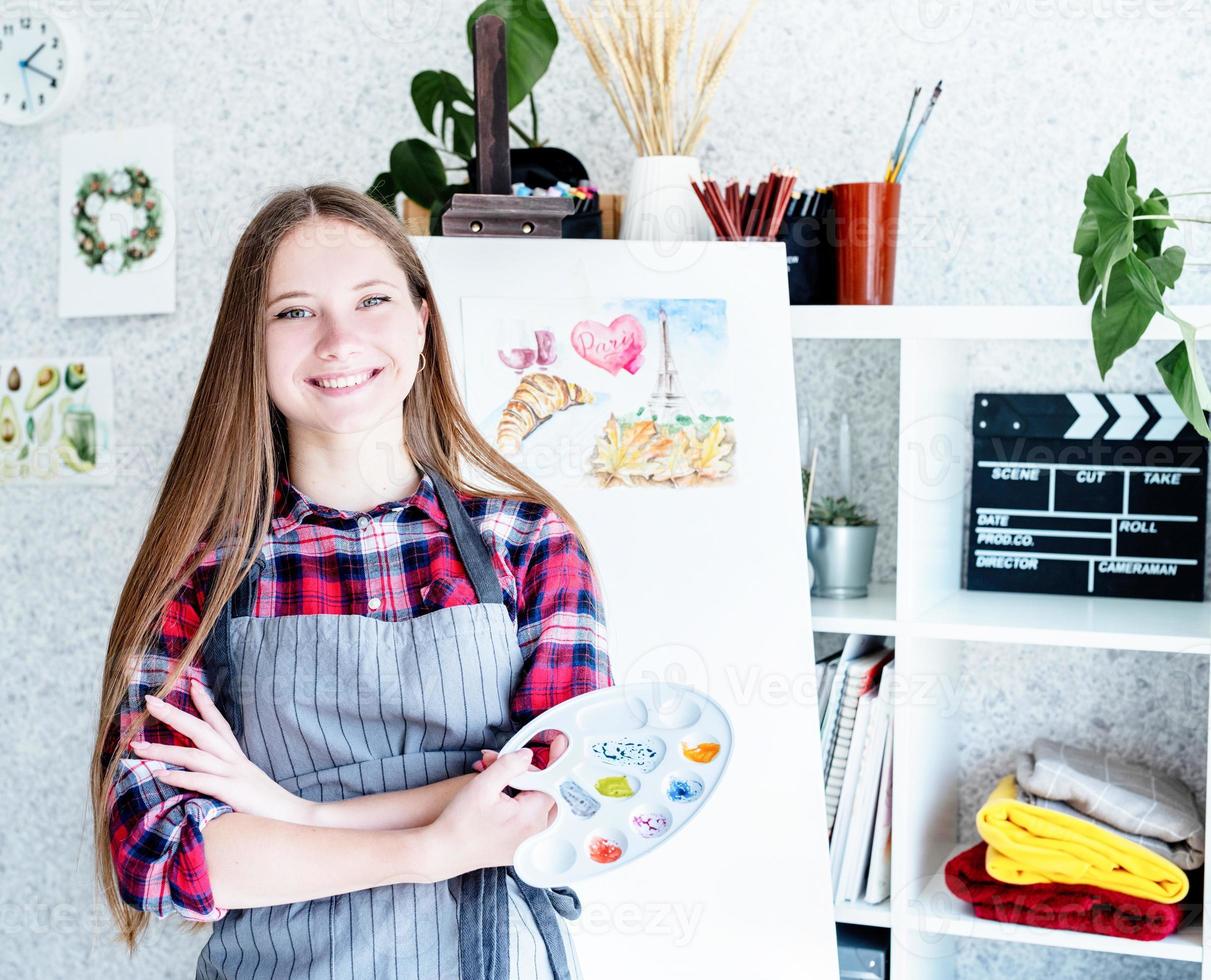 jonge vrouw kunstenaar met kleurenpalet aan het werk in haar studio foto