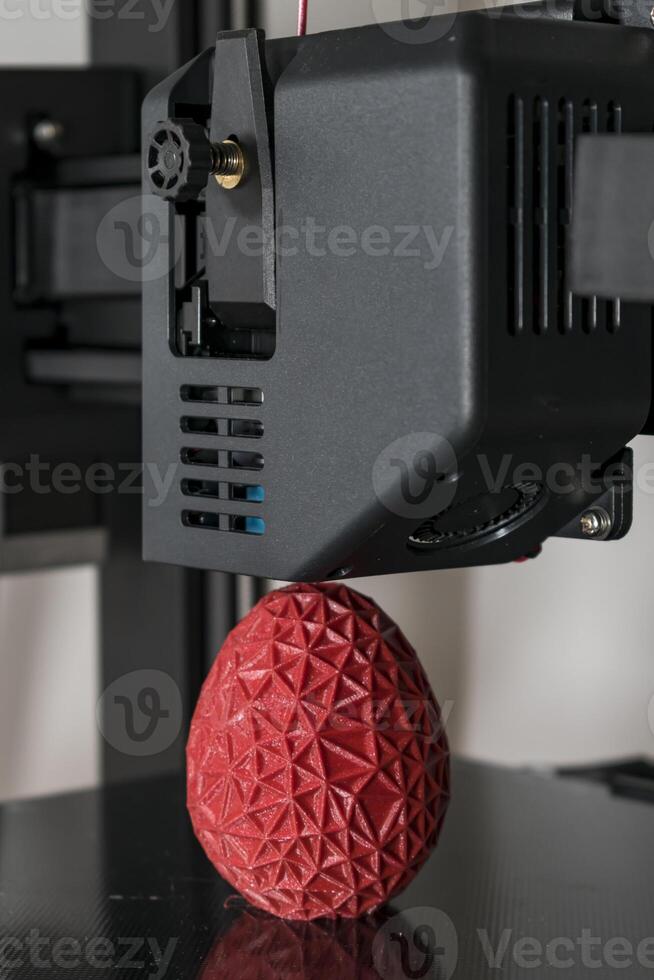 dichtbij omhoog van een 3d printer het drukken een rood veelhoekige ei foto