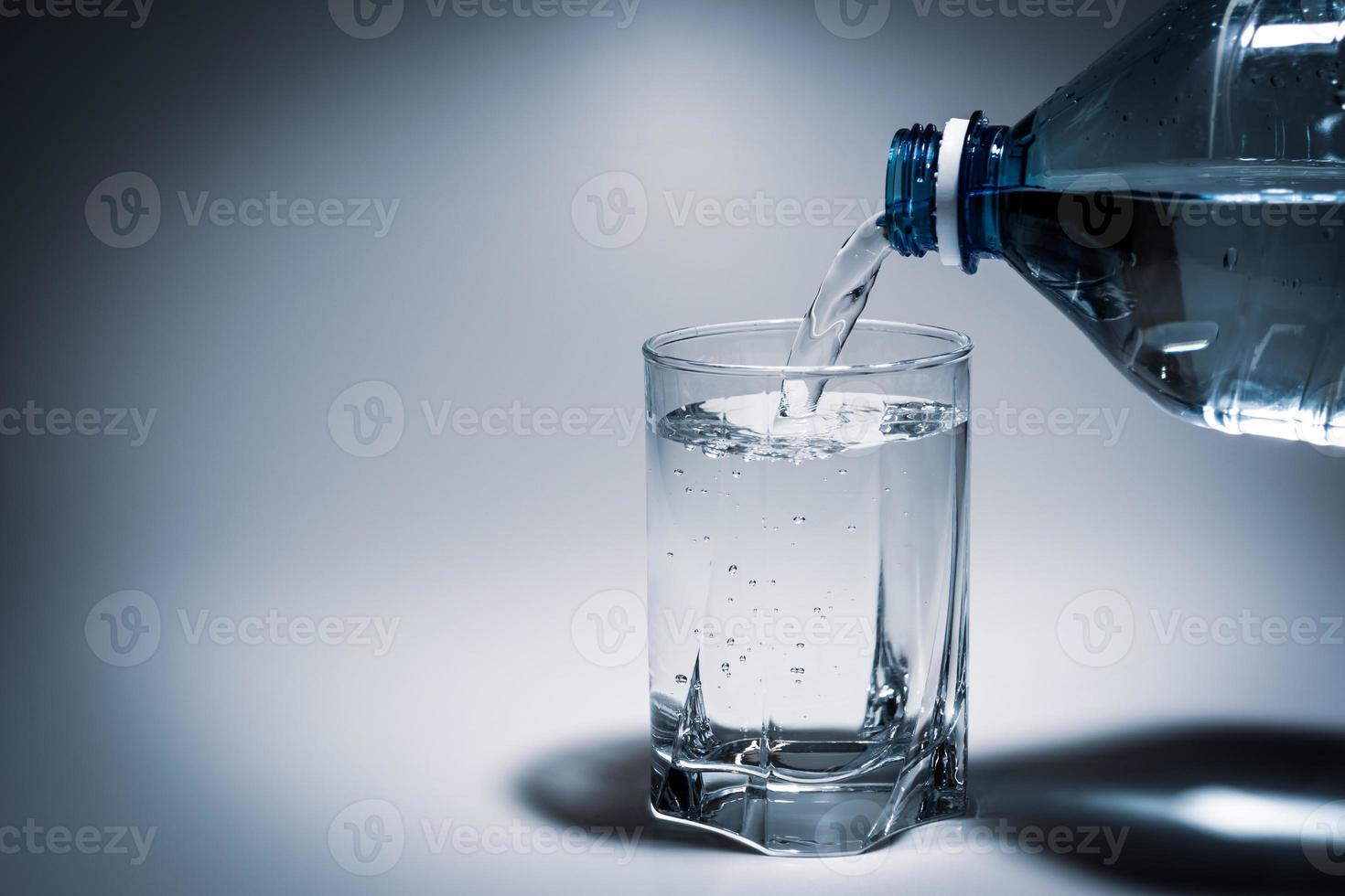 water uit een plastic fles in een glas gieten foto