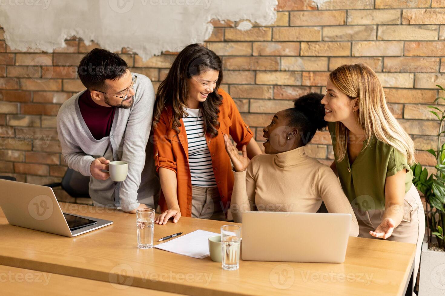 jong multi-etnisch opstarten team werken door de steen muur in de industrieel stijl kantoor foto