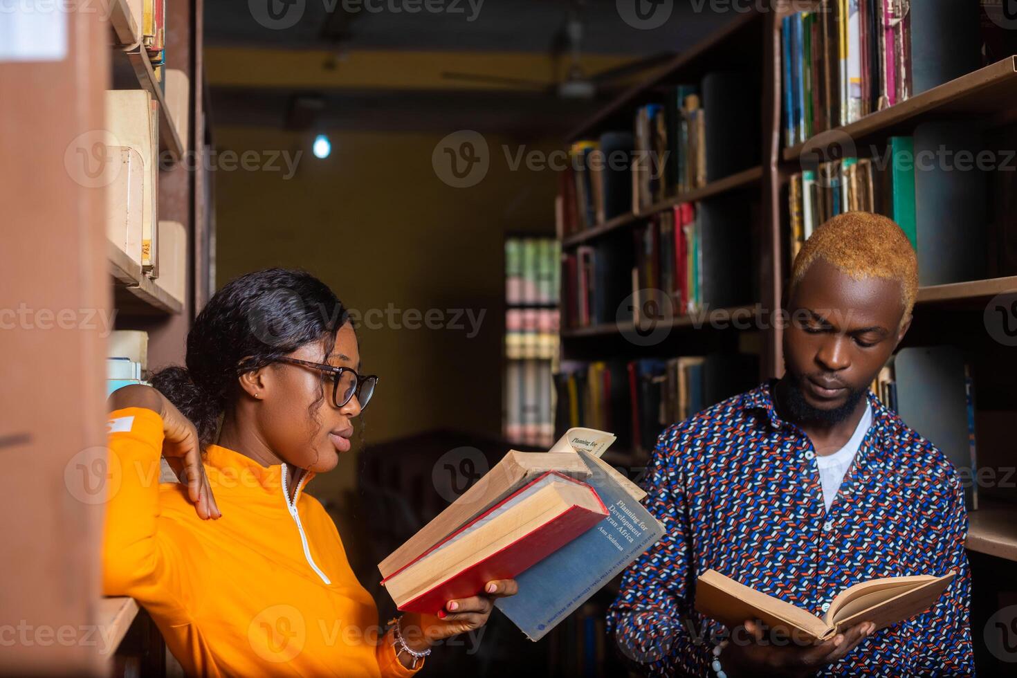 hoog school- - twee studenten met boek in de bibliotheek aan het studeren voor tentamen foto