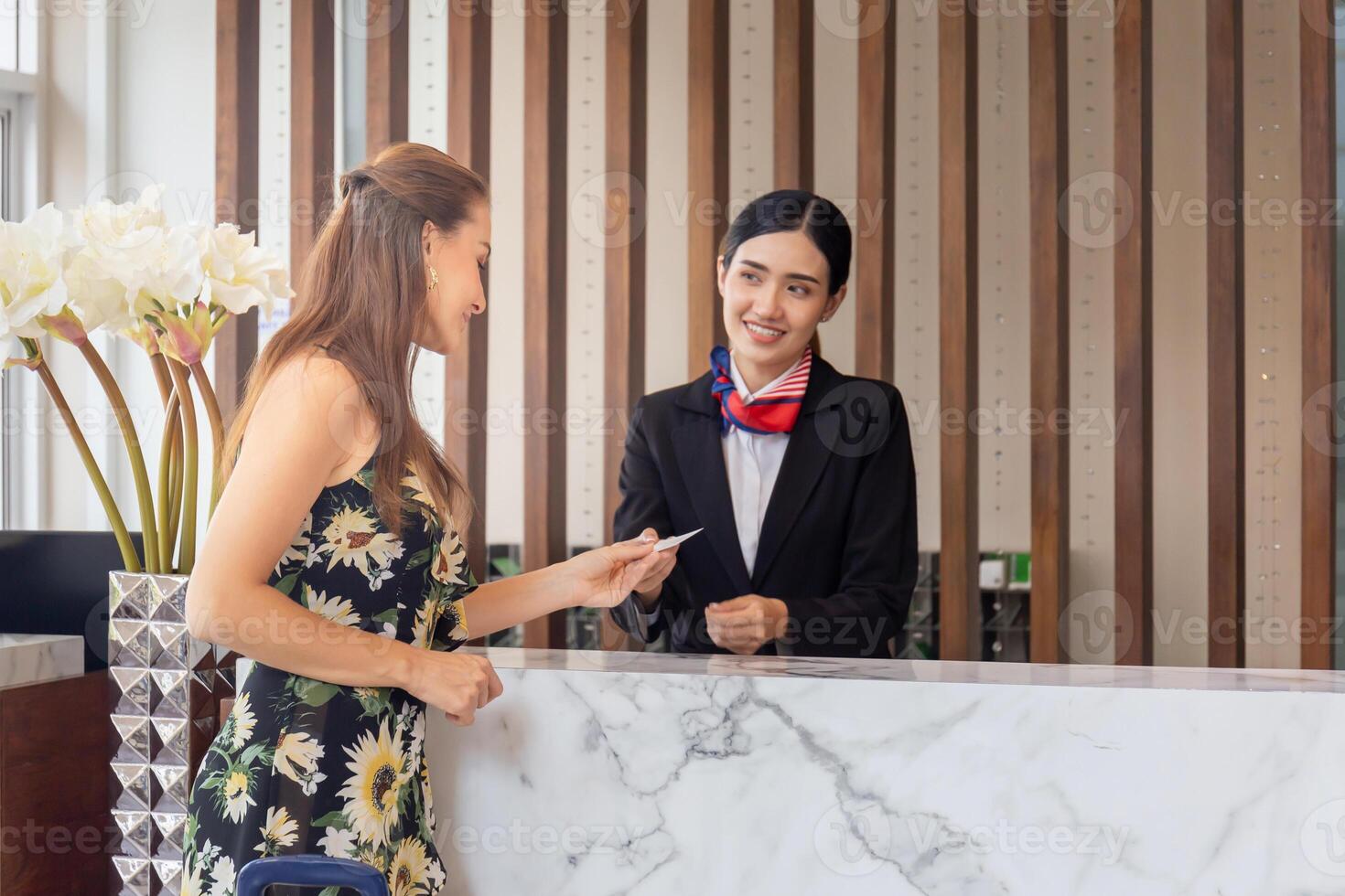 focus Aan vrouw reizigers met zak reizen bagage Check in Bij de hotel met wazig glimlachen vrouw receptioniste foto